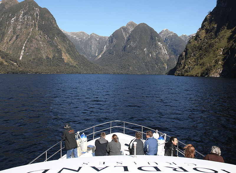 Group of people enjoying the scenery on the bow of the Southern Secret while it's cruising on Doubtful Sound.